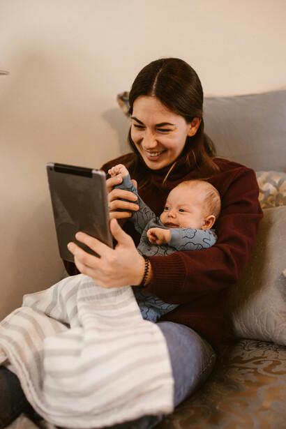A quiet moment of connection: mother cradling her baby while on a video call with loved ones