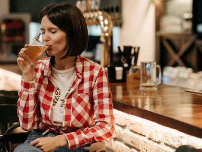 A woman sits alone in a pub, quietly enjoying a glass of beer