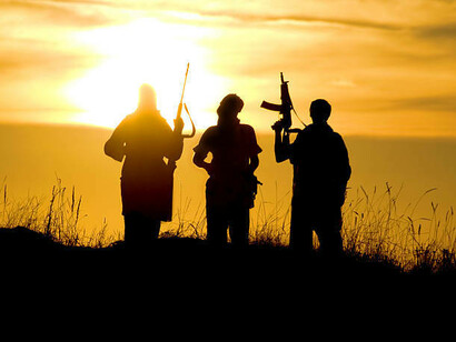 Silhouettes of militants crossing a sunlit desert at dusk