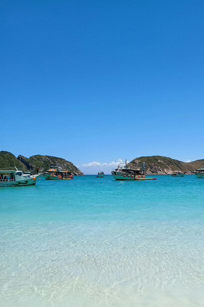 A peaceful scene of boats resting in shallow, turquoise waters, framed by rolling hills