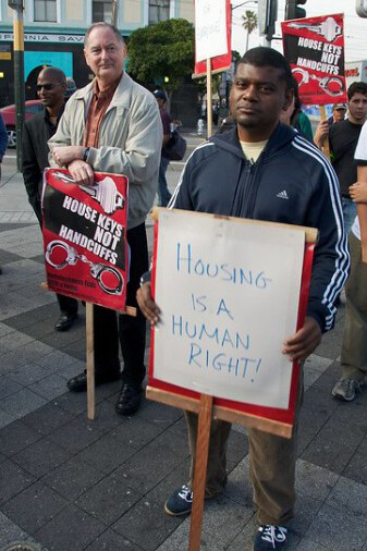 Housing activists march in protest, holding signs that read 'Housing is a right,' demanding fair and affordable living conditions