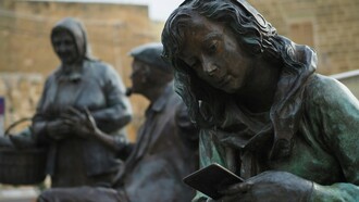 A statue of a young woman absorbed in her smartphone with headphones on, representing the quiet isolation created by constant digital immersion