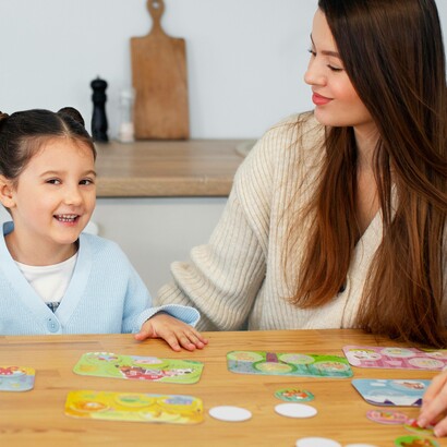 Bambina e adulto che giocano insieme con un gioco da tavolo, adatto a bambini della scuola dell'infanzia