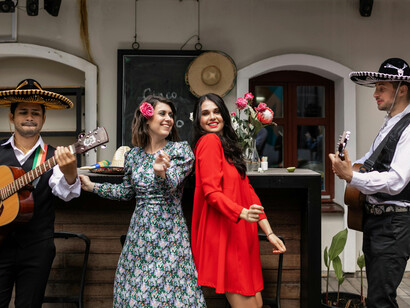 A woman dances in a flowing dress while men in sombreros play guitars beside her