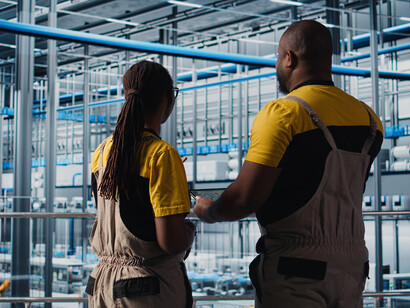 Two smart factory engineers use a tablet to implement automated workflows powered by artificial intelligence, driving digital transformation