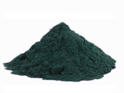 Spirulina powder in vibrant green color on a white table, a supplement made from blue-green algae