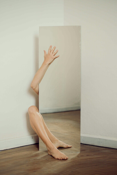 La luz entra por la ventana en franjas irregulares, iluminando su rostro por instantes y dejando sombras que se arrastran por la madera del suelo