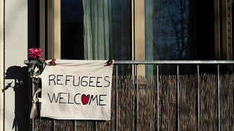 A sign reading "Refugees Welcome" displayed on a building