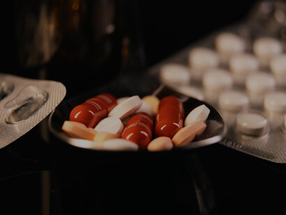 A spoon overflowing with various pills, placed on a table, showcasing a collection of multivitamin supplements