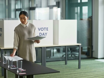 Woman placing a white ballot paper on the table, preparing for election day as part of the democratic process