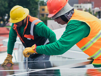 Technicians mounting solar panels on the roof of a building
