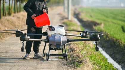 Individual refilling a big agricultural drone for farming use