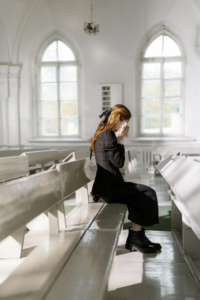 A woman in a black dress sitting alone inside a church