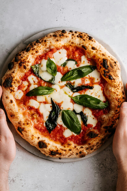 A devotee of the Holy Pizza lifts a slice, ready for the first bite