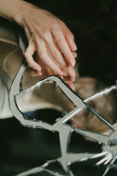A woman's reflection fractured in a broken mirror