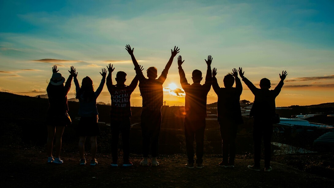 Silhouettes of people holding hands at sunset, symbolizing unity and togetherness