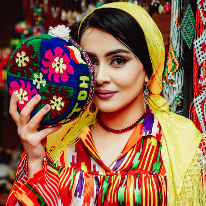 Uzbek woman with yellow scarf holding a colorful handmade bag, traditional craft and culture