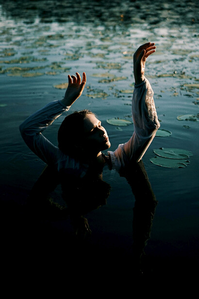 A woman drifting peacefully across the water, surrounded by graceful water lotuses in bloom