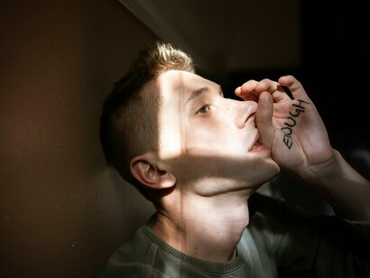 A man with the word "enough" written on his hand, demonstrating the inner voice that tells us we are not good enough and that we need to strive for more