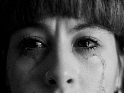 A woman's face streaked with tears, representing a deep sense of sorrow and pain that persists long after the dust settles