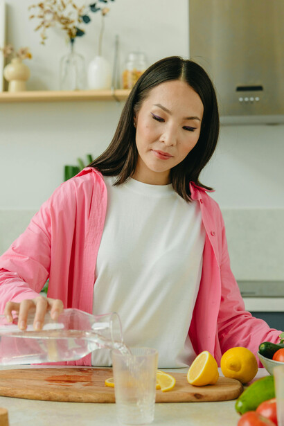 A woman enjoying a smoothie with a nutritious plate filled with fresh fruits, vegetables, and other healthy foods