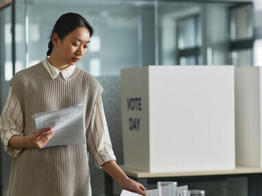 Woman setting down a white paper on the table, symbolizing preparations for election day and the practice of democracy