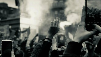 People filming an act of protest, demonstrating how young people use social media to spread awareness during times of conflict and war
