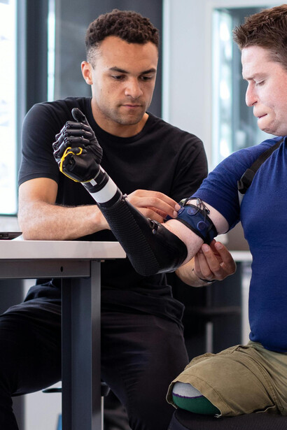 An engineer working meticulously to fit a prosthetic arm for an individual with a disability, improving their independence