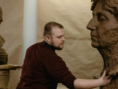 A sculptor shaping clay in a cluttered studio, where the chaos of creation becomes a personal sanctuary