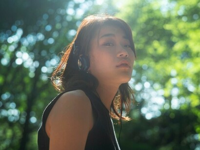 A silhouette of a woman wearing headphones in a natural setting, lost in deep thought