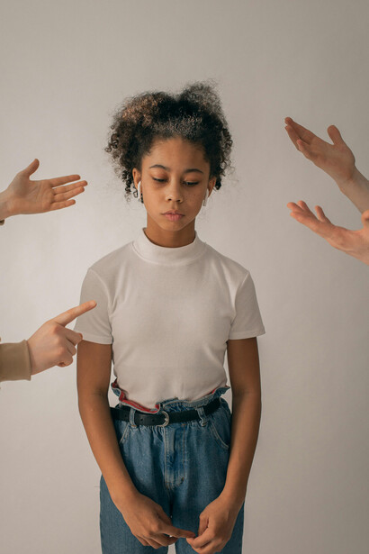 A distressed Black teenage girl covering her mouth, symbolizing the hidden fear and vulnerability brought on by online manipulation and social pressure
