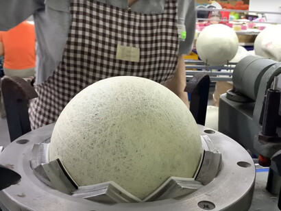 A woman is engaged in the process of producing footballs