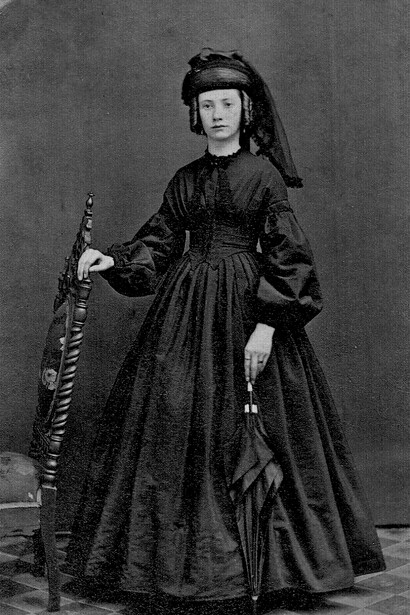 Victorian mourning customs: a woman dressed in a dull black Victorian mourning gown, reflecting the era’s traditions