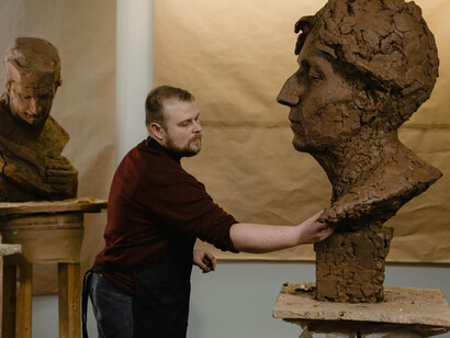 In the heart of his messy art space, a man molds a clay sculpture—each movement a quiet dialogue with his inner world