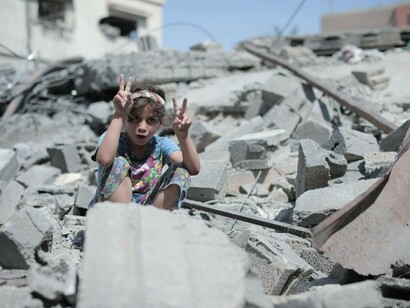 A girl sitting on the rubble of a collapsed building in Gaza, symbolizing the devastation and humanitarian crisis