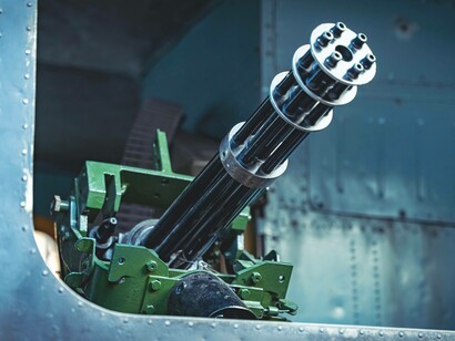 Mitragliatrice Gatling su parete metallica: "i conflitti armati nel mondo proliferavano e lo stand della ditta Peng all’ultima fiera delle armi di Norimberga era stato il più visitato di tutti"