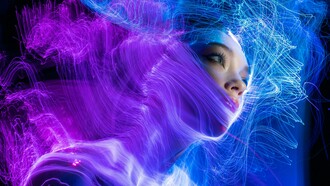 A woman with striking blue eyes illuminated by soft blue string lights