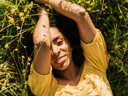 Woman in yellow lying on grass, absorbing sunlight for vitamin D