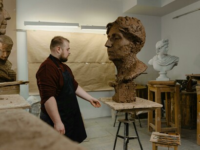 A man working on a clay sculpture in his artist's studio—a messy art space that serves as his personal sanctuary