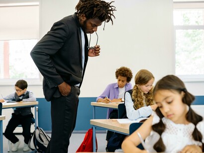 A male teacher with students in a primary school classroom