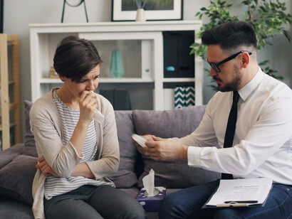 A man and a woman sitting on a couch while the woman talks through her therapy session