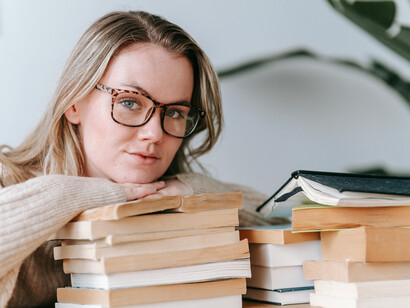 Wrapped in a sweater, glasses on, a woman enjoys her book in the comfort of home—every inch a book lover's dream