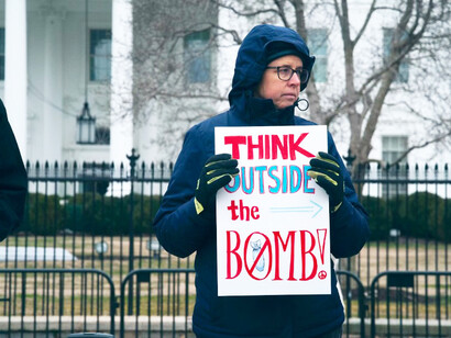 A man holds a sign that reads 'Think Outside the Bomb' during a daytime protest, USA