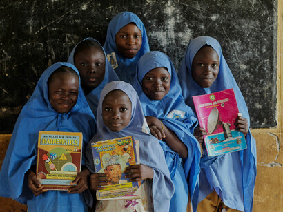 Young girls wearing blue hijabs inside a classroom, symbolizing rural development through access to education