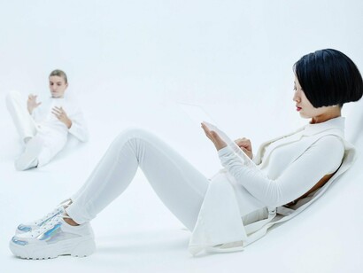 A man and a woman sitting in the room, with their eyes fixed on tablets, representing the modern habit of choosing devices over dialogue