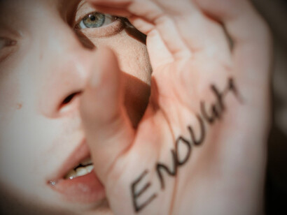 A man with the word "enough" scrawled on his hand, representing the common question that many people ask themselves: am I enough?