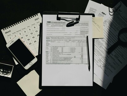 A workspace covered in tax files, notes, and a calculator, symbolizing the detailed financial checks needed to uncover graft schemes