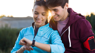 Young couple using their smartwatches to track fitness data post-run