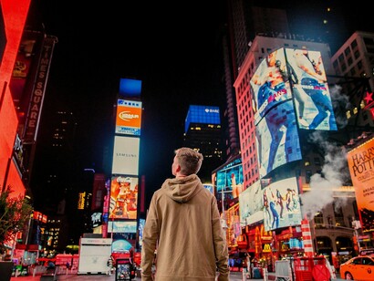 Rua repleta de outdoors e propagandas diversas. Embora pareça promissor, o avanço do AI Max precisa ser analisado com cautela. Automatizar tarefas operacionais é positivo, mas só até certo ponto