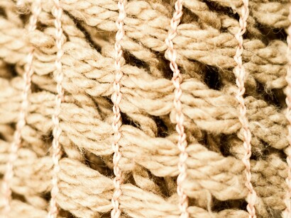 Dettaglio ravvicinato di una trama di tessuto grezzo, che mostra fibre intrecciate a formare un disegno a maglia larga: "Se sciogliamo i nodi, se separiamo ogni filo dagli altri, non otterremo una versione semplificata del sistema, ma la sua dissoluzione..."